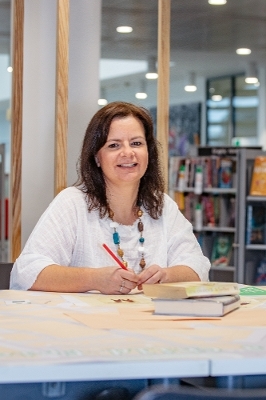 Rachael sat at a table holding a pencil with two books on the table