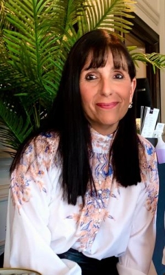 Joanne sat down with a white shirt on with an orange and blue pattern.